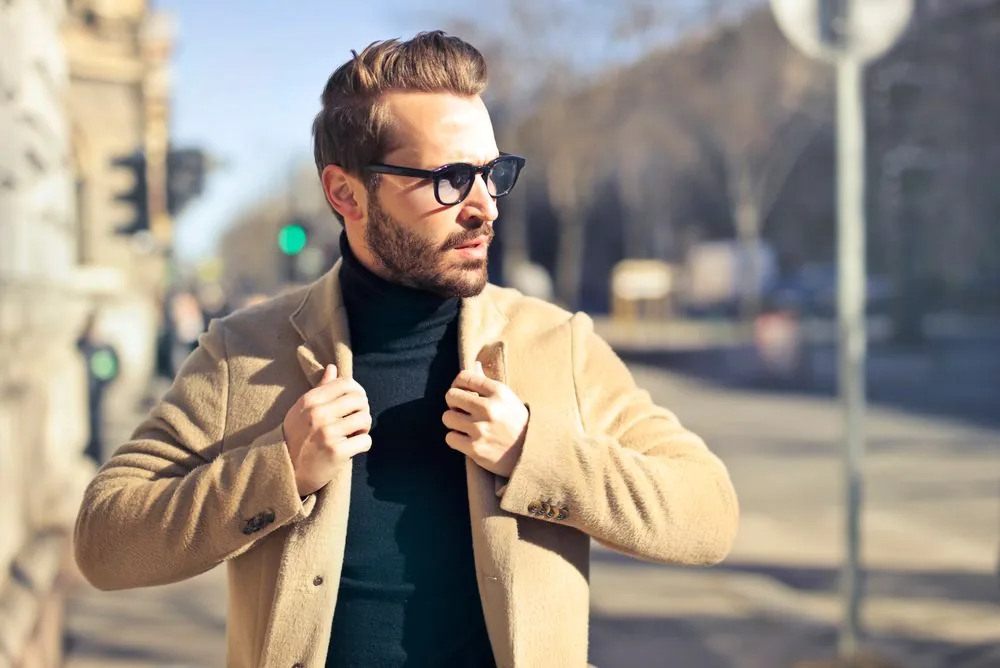 Camel coat worn over a dark roll-neck jumper