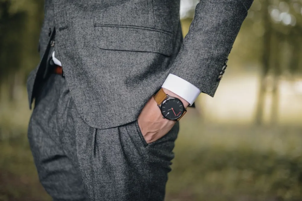 Grey textured suit with a white shirt cuff and leather-strap watch
